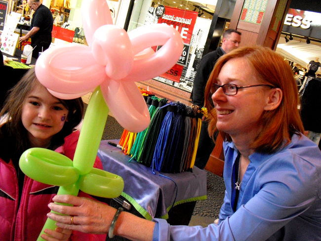 Janice handing a girl a Balloon Flower